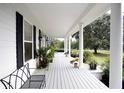 Long front porch with white columns, black shutters, and potted plants at 23337 Lake Lindsey Rd, Brooksville, FL 34601