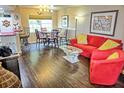 Cozy living room with dark floors, red sofa and chair, glass coffee table and dining area at 2077 Wetland Pt # 1103, Lutz, FL 33558