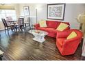 Bright living room featuring a red sofa, chairs, hardwood floors, table and a large window at 2077 Wetland Pt # 1103, Lutz, FL 33558