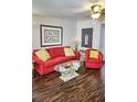 Well lit living room with red furniture, a glass coffee table and unique decor at 2077 Wetland Pt # 1103, Lutz, FL 33558