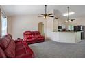 Living room with red reclining sofas, ceiling fan, and view into the kitchen at 4336 Lightfoot St, Spring Hill, FL 34609