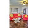 Bright living room featuring a red sofa and chair, coffee table, and dark hardwood floors at 2077 Wetland Pt # 1103, Lutz, FL 33558