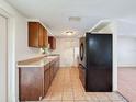 Kitchen features tile floors, wood cabinets, and a black refrigerator; open to the living area at 7206 Ashwood Dr, Port Richey, FL 34668