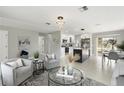 Bright living room with open layout, modern lighting fixtures, stylish furniture, and a view into the well-lit kitchen at 7332 Mako Dr, Hudson, FL 34667