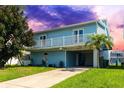 Two-story waterfront home with light blue exterior and balcony at 7637 Hatteras Dr, Hudson, FL 34667