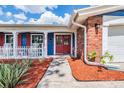 Welcoming front entrance with a red double door, brick accents, and a neatly landscaped walkway leading to the home at 3849 Claremont Dr, New Port Richey, FL 34652