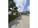 Inviting single-Gathering home with a well-kept lawn, attached garage, and a charming stucco facade, all under a sunny sky at 8088 Spanish Oak Dr, Spring Hill, FL 34606
