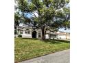 Well-maintained single-story home with a sprawling green lawn, mature trees, and a serene, inviting curb appeal at 8088 Spanish Oak Dr, Spring Hill, FL 34606