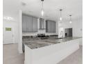 Modern kitchen with gray cabinets and granite island at 15214 Mount Sparrow Rd, Brooksville, FL 34614