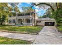 Two-story house with a wrap-around porch, mature trees, and detached garage at 321 S Brooksville Ave, Brooksville, FL 34601