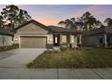 Single story home with a two-car garage, front porch, and manicured lawn at sunset at 11512 Weaver Hollow Rd, New Port Richey, FL 34654