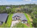 An aerial view captures the property's spacious lot and mature trees, with blue accents on the facade at 6109 Dusk Rose Ln, Brooksville, FL 34601