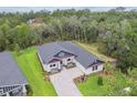 Aerial view of an elegant single-Gathering home with a lush green yard and mature trees in the background at 6109 Dusk Rose Ln, Brooksville, FL 34601