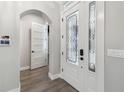 Bright foyer showcases a decorative glass front door, arched doorway, and modern wood flooring at 6109 Dusk Rose Ln, Brooksville, FL 34601