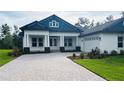 Charming single-story home boasting manicured landscaping, a paver driveway, and a modern blue and white exterior at 6109 Dusk Rose Ln, Brooksville, FL 34601
