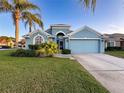 Light blue house with two-car garage and palm trees at 2718 Tidal Creek Dr, Holiday, FL 34691