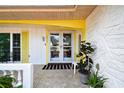 Inviting front porch with double doors, textured walls, neutral tile, and bright yellow trim at 12212 Buttonwood Row, Hudson, FL 34667