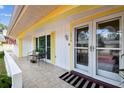 Welcoming front porch showcasing double doors, yellow trim, and a seating area at 12212 Buttonwood Row, Hudson, FL 34667