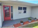 Front porch featuring a red door, decorative plants, and a nearby window at 3544 Wilson Dr, Holiday, FL 34691