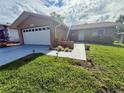 Inviting single-story home with a well-maintained lawn, shrubs, and a driveway leading to the attached garage at 10521 Mira Vista Dr, Port Richey, FL 34668