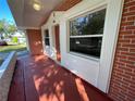 Front porch with brick columns and a red door at 5319 Whippoorwill Dr, Holiday, FL 34690