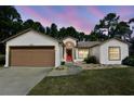 Exterior view of a house with a brown garage door and red front door at 10369 Golden Ave, Weeki Wachee, FL 34613