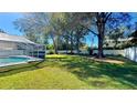 Lush backyard featuring healthy lawn, tall trees, fence, and a screened-in patio at 6206 Soaring Ave, Temple Terrace, FL 33617
