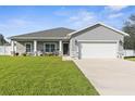 Gray house with white garage door, stone accents, and a well-maintained lawn at 13031 Pacific Nighthawk Ave, Weeki Wachee, FL 34614