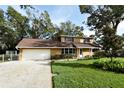 Tan house with brown roof and attached garage, ample yard space at 15473 Darien Way, Clearwater, FL 33764