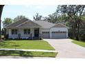 Inviting single-story house featuring a lovely front porch, lush green lawn, and an attached two-car garage at 6392 Summit View Dr, Brooksville, FL 34601