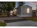 Inviting exterior with gray siding and a fresh deck, lit windows on the front of the home at dusk at 4304 Buena Vista Ln, Holiday, FL 34691