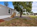 Charming exterior with gray siding, featuring a deck, tree in the front yard and well-kept landscape at 4304 Buena Vista Ln, Holiday, FL 34691