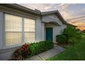 Inviting home entrance featuring a teal door, beautiful landscaping, and a welcoming facade at 1931 Sassafras Dr, Wesley Chapel, FL 33543