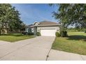 Single-story home with a long driveway, two-car garage, manicured lawn and landscaping at 2293 Dog Leg Ct, Brooksville, FL 34604