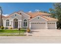 Charming home featuring a three-car garage, beautiful red tile roof, and lush green landscaping at 10441 Garda Dr, Trinity, FL 34655