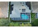 An aerial view showcasing a home with a screened-in pool and solar panels on the roof at 2533 Wood Pointe Dr, Holiday, FL 34691