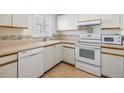 Bright kitchen features white appliances and wood-look flooring at 4222 Northampton Dr, New Port Richey, FL 34653