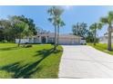 Beige single-Gathering house with a three-car garage and palm trees at 12224 Mango Ct, Spring Hill, FL 34609