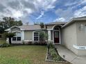 Lovely home featuring a well-manicured lawn and beautiful landscaping leading to an arched entryway with a red front door at 10448 Canary Ave, Weeki Wachee, FL 34613