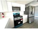 Modern kitchen with white shaker cabinets, quartz countertops, and stainless steel appliances at 7340 Gulf Highlands Dr, Port Richey, FL 34668