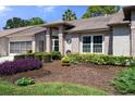 Landscaped front yard with manicured shrubs and a brick house with screened garage at 7425 Baywood Forest Cir, Spring Hill, FL 34606