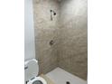 Modern shower with beige tile and a white toilet at 7142 Carlow St, New Port Richey, FL 34653