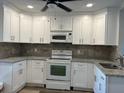 Bright kitchen featuring white cabinets, granite countertops, and modern appliances at 7142 Carlow St, New Port Richey, FL 34653