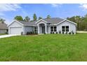 Newly built home with gray siding, a two-car garage, and a spacious lawn at 12440 Maycrest Ave, Weeki Wachee, FL 34614