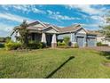 Two-story home with gray exterior, three car garage, and a landscaped yard at 19907 Tattnall Way, Brooksville, FL 34601
