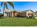 Tan one-story house with a two-car garage and lush lawn at 6604 Rosemont Ct, New Port Richey, FL 34655