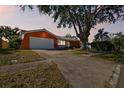 Bright orange ranch home with a large tree and driveway at 465 Meadowlark Ln, Palm Harbor, FL 34683