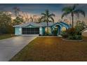 Evening view of a teal house with palm trees and a screened garage at 6225 Hancock Ave, Spring Hill, FL 34608