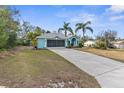 Front view of a teal house with a long driveway and palm trees at 6225 Hancock Ave, Spring Hill, FL 34608