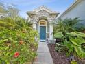 Stone and column entryway with lush landscaping and a teal front door at 92 Randolph Ave, Spring Hill, FL 34606
